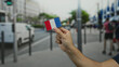 © Krakenimages.com - Man holding embroidered france flag patch on city street background showcasing patriotism and outdoor urban scene familiar in european towns.