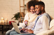 © Prostock-studio - Loving afro couple choosing film on laptop, resting together at cozy winter evening, free space