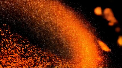 Poster - Abstract macro video shows bright orange particles dispersing and fading into the dark background, creating a textured, glowing effect.