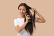 © Pixel-Shot - Beautiful young happy woman applying hair spray on beige background