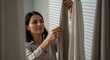 © ferifadli - Close up of a woman carefully installing window curtains