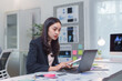 © Crystal - Asian businesswoman working diligently, comparing information from documents and a laptop in a sleek, modern office environment
