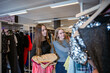 © Cavan Images - Two young women browsing clothes at second hand clothing store