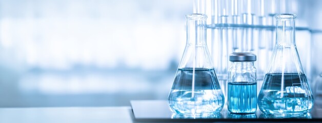 Aufkleber - Erlenmeyer flasks and vials containing blue and clear liquids on a laboratory table, performing a chemical experiment