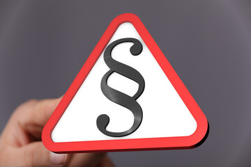Aufkleber - Hand holding a red triangle warning sign with a paragraph symbol.  Legal concept.