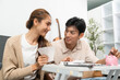 © wichayada - Financial Awareness and Connection. Couple sharing smiles while reviewing savings at home.