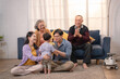 © Hip.hub - Family gathering with grandparents, parents, and child enjoying quality time at home during a sunny afternoon