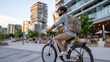 © Shiki - A commuter rides an electric bike along a city sidewalk, dressed in business-casual attire with a backpack, blending urban mobility with eco-conscious travel in a modern, active lifestyle scene.