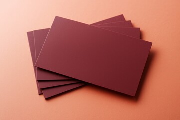 Poster - Blank burgundy business cards fanned out on soft peach background for branding or promotion concept with clean and minimal design template.