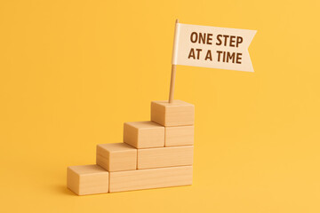 Poster - Progress and achievement are symbolized by smooth wooden blocks stacked like stairs with a flag that encourages steady advancement