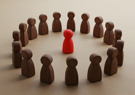 Leadership concept with red figure standing out from circle of brown wooden figures on table top view
