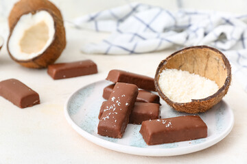Wall Mural - Plate with tasty chocolate covered coconut candies on white background