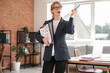© Pixel-Shot - Young female accountant in eyeglasses with clipboards pointing at something in office