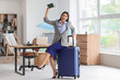 © Pixel-Shot - Happy businesswoman with packed suitcase, passport and tickets before vacation in office