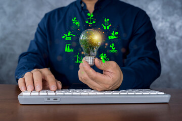 Wall Mural - Businessman holding eco light bulb with green energy icons, sustainable innovation and technology concept
