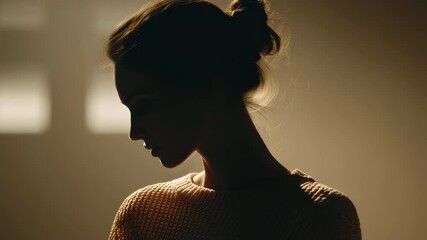 Poster - Warm light illuminates a fashionable young woman posing in profile against a wall, creating a captivating silhouette, showcasing her elegant posture and serene expression in a studio setting