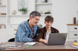 © New Africa - Smiling father and his son doing homework with laptop at table indoors