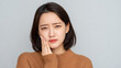 © aironamad - Young Woman Holding Her Cheek with a Painful Expression Showing Signs of Toothache and Facial Discomfort