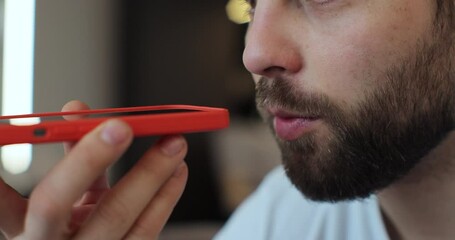 Close-up of bearded man recording answering by audio message in social network on mobile phone. Man call on phone closeup, use loudspeaker at home.