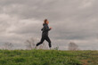 © Ljustina - Young sportswoman running in a meadow on a cloudy day