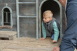 © Elena - Child Crawling Out of Wooden Playhouse Door with Adult Nearby