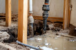 © xadartstudio - Damaged pipes leaking water during home renovation muddy floor wooden supports