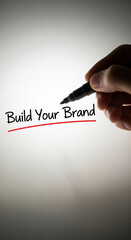 Poster - Hand writing Build Your Brand on white surface with black marker, underlined in red, showcasing business growth concept with free space for text or logo