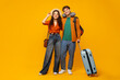 © Home-stock - Happy European spouses ready for vacation, standing with suitcase, man wearing travel neck pillow and backpack, couple posing over yellow background