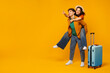© Home-stock - Crazy travel offer. Overjoyed woman piggybacking man, standing with luggage and pointing at free space on yellow background, full length