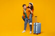 © Home-stock - Overjoyed couple ready for vacation, woman piggybacking man, standing with luggage suitcase and having fun on orange background, full length