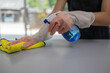 © Kield KD - A woman is cleaning a counter with a yellow cloth and a spray bottle. The counter is made of granite and is in a kitchen