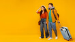 © Home-stock - Travel offer. Happy European couple walking with suitcase and looking at copy space on orange background, full length. Spouses going to vacation together