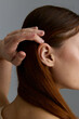 © SHOTPRIME STUDIO - Beauty woman with smooth auburn hair gently holding strands near ear, showcasing natural texture and minimalistic style in soft studio lighting.