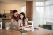 © Migma_Agency - Happy couple paying bills online and managing home budget using laptop