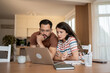 © Migma_Agency - Focused couple reading important information on laptop at home