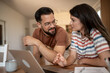 © Migma_Agency - Couple using laptop and discussing home finances at table