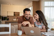 © Migma_Agency - Happy couple watching funny videos on laptop at home