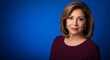 © Tida - Professional Woman Portrait Against Blue Background - A headshot of a woman with shoulder-length brown hair wearing a maroon top against a solid blue background
