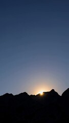 Wall Mural - Silhouette of rugged mountain peaks against a vibrant twilight sky, capturing the serene beauty of nature at dusk with a peaceful atmosphere