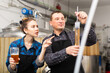 © JackF - Man brewmaster measuring beer sample with alcoholometer. His female colleague standing beside and pointing finger at graduated glass.