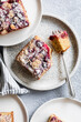 © The Picture Pantry - Top view of berry crumb cake slices on white plates with a fork and striped napkin.