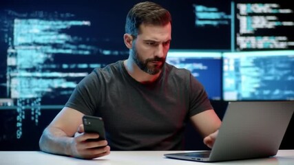 Poster - Bearded Man Holding Phone Works on Laptop with Multiple Monitors Displaying Code in Dark Blue Background