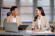 © wattana - Two business professionals planning project together at desk with laptop and notes.