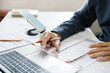 © Lek - close-up shot, hand of businessman reviewing document at office. legal expert, professional lawyer working with computer reading and checking financial documents and business contract