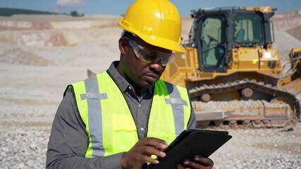 Poster - African American Construction Worker Inspecting with Tablet in Yellow Hard Hat and Safety Vest Near Heavy Yellow Bulldozer On Construction Site