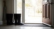 © Oxana39 - Black rubber boots are placed near an open door, leading to a bright outdoor area. A welcome mat is visible on the floor.