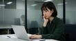 © SITI - Focused young Asian woman working on laptop in modern office environment with glass partitions and lighting