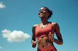 © Vadym - Young black woman athlete smiling during run, fitness training. Happy runner enjoys outdoor workout, marathon prep on sunny summer day with blue sky. Female sports model.