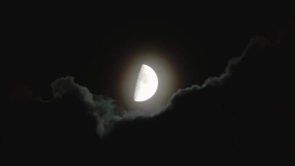 Wall Mural - Moon covered by clouds in dark night sky. Natural skyscape with flying black cloud