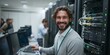 © Oleksandr - IT Professional in Data Center: A smiling IT technician stands in a server room, highlighting data management and infrastructure.